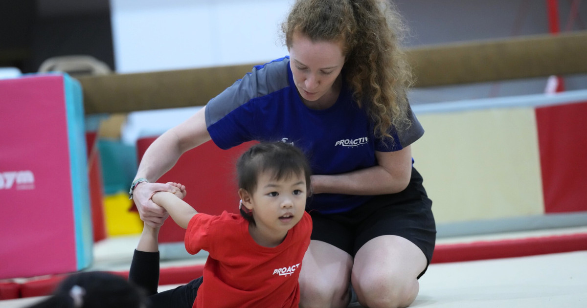 A child performing a perfect bridge pose on a blue gymnastics mat.
