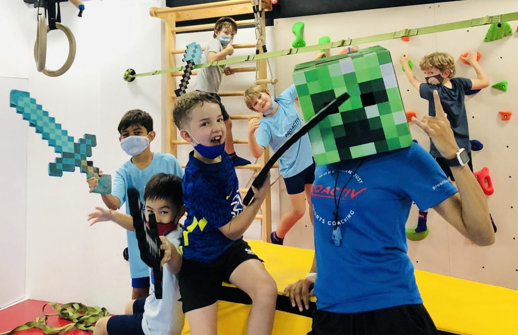 Kids participating in a group huddle with their coach during a school holiday sports program.